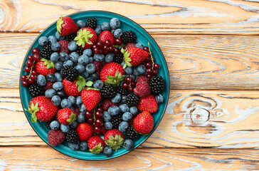 Mix of ripe colorful berries in bowl photography . Blueberry , strawberry , raspberry , blackberry and red currant . Top view