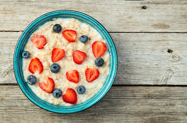 Homemade breakfast . Oatmeal with milk and berries . Top view