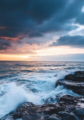 Obraz premium Ocean Waves Crashing On Rocky Shore At Sunset