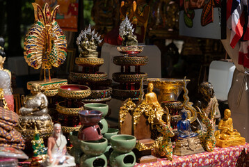Fototapeta premium Thai art, figures, bowls, religious symbols, Buddha statues, offered at a market in the city. Arts and craft, trading, Souheast Asia.