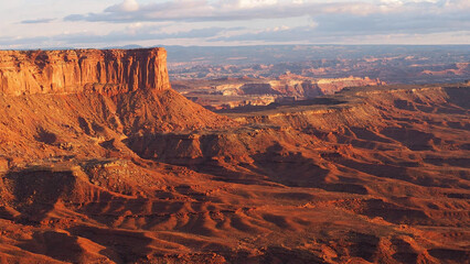 Expansive desert canyon landscape with rugged cliffs under soft sunlight