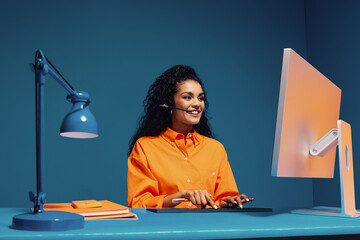 Smiling female agent wearing headset and typing on keyboard