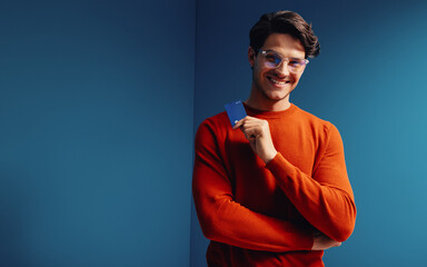 Young man with bank card in vibrant colorblocking environment depicting financial confidence