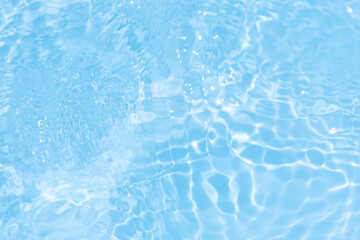 Blue water with ripples on the surface. Defocus blurred transparent blue colored clear calm water surface texture with splashes and bubbles. Water waves with shining pattern texture background.