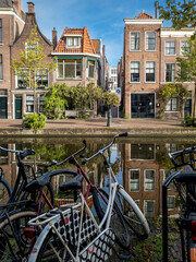 Leiden&rsquo;s canals, lined with historic Dutch buildings and lush greenery, reflect the serene beauty of the city. The calm waters and picturesque architecture create a tranquil urban scene.