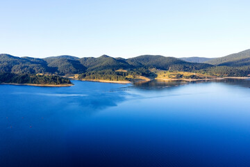 Lake and mountains surrounded by forests in Bulgaria. Fish farms of trout and other fish on the lake. Aerial shot with a drone