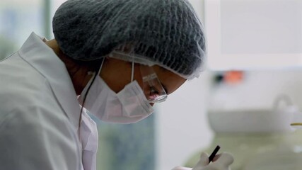 Dentist focusing intently on a dental procedure, wearing protective mask and glasses in a modern clinic with sterile equipment and a clean environment