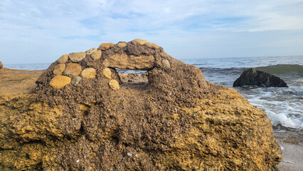A structure made of stones and sand on the Black Sea coast. The sea with black stones in the background