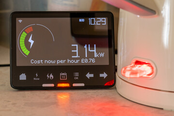 A energy use and cost concept with a smart energy meter showing the amount of energy in use next of...