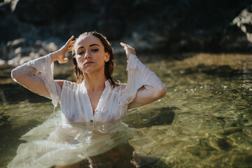 Woman in a white dress standing in a calm river setting. She appears relaxed and thoughtful in a beautiful natural environment.