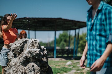 Lively group of friends enjoying a playful moment by the fountain in a sunlit park setting on a bright day.