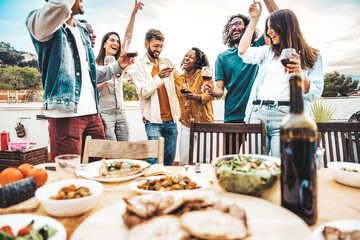 Group of young people having fun drinking red wine on balcony rooftop bbq dinner party - Happy...