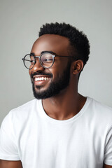 Obraz premium Smiling man, A pleased dark-skinned man with an unshaven face and glasses, wearing a casual white t-shirt, joyfully reacts to positive news with a broad smile