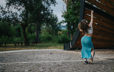 A young girl expresses joy while dancing in a park, wearing headphones and a flowing blue skirt. The scene captures freedom and happiness in an outdoor setting.