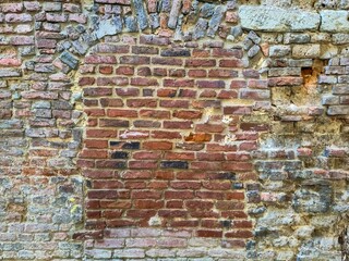 View of a very old brick wall in which a window has been bricked up.