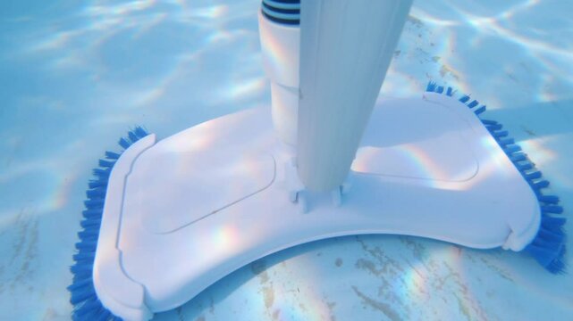 Cleaning the bottom of the pool with an underwater vacuum cleaner with a brush