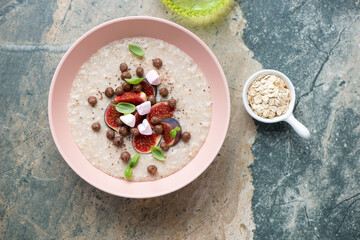 Roseate bowl with figs oatmeal on a beige and grey granite background, horizontal shot, top view