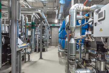 The facility features an extensive network of silver pipes and machinery, with blue tanks lining...