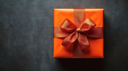 A beautifully wrapped orange gift box with a delicate brown ribbon, perfect for any special occasion.