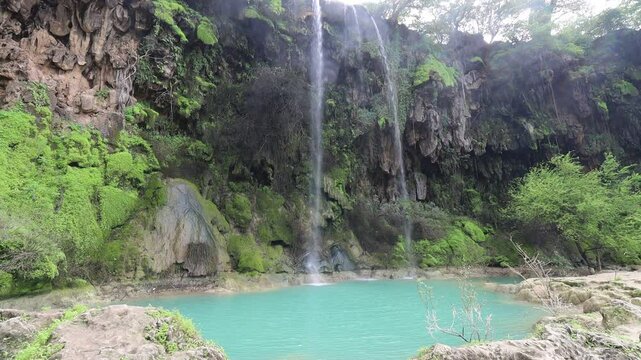 ain athum waterfall in salalah oman with green grass and small blue pond