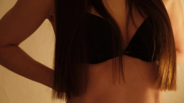 Sexy girl takes off her black bra. Young confident woman dancing striptease erotic dance. Brunette with long hair. Concept of love and foreplay of sex. Beautiful fit body. Arousal and lust. 4K