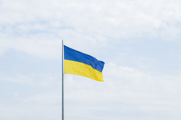 Ukrainian waving flag blue yellow colors on a high pillar with cloudy sky background panorama view