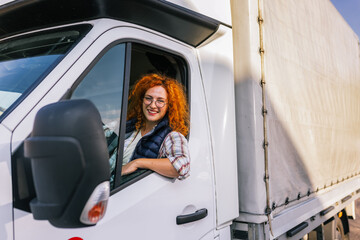 Portrait of professional woman truck driver looking out the window. People and industrial...