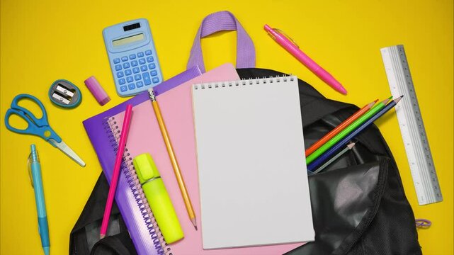 Black school backpack full of school supplies on yellow background. Stop motion animation

