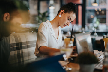 Focused businesspeople working together in a cozy coffee bar with laptops and documents. Collaborative and productive environment.