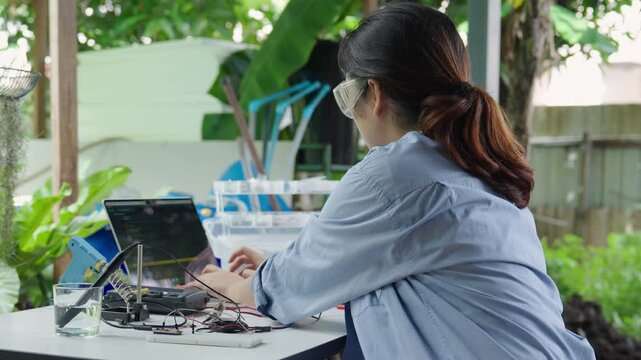 Asian woman programming microcontroller to control Analog Dissolved Oxygen Sensor to find the appropriate value of oxygen in water for use in agriculture in aquaculture. IoT Internet of Thing.