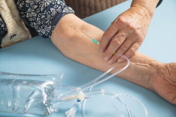 Obraz premium Hand of elderly patient with IV drip with infusion bag.