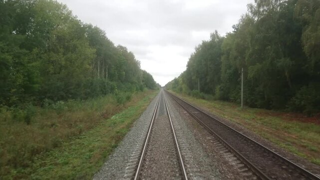 The rails run away into the distance. Moving backwards. The Russian Railway. Video footage from the last carriage of the train. An autumn or summer cloudy day.