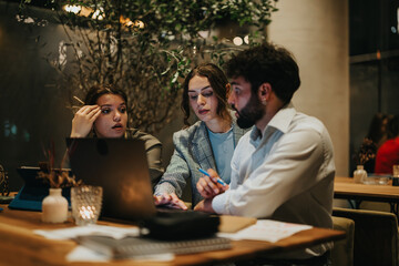Businesspeople working together late at night in a coffee bar, focused on finishing a project and meeting deadlines.