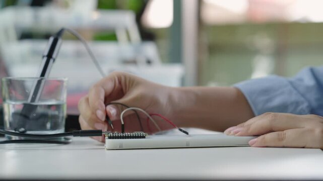 Close-up, Hand of woman installing analog dissolved oxygen sensor to microcontroller. Agriculture and aquaculture. Internet of Things (IoT).