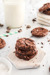 Stacked brownie cookies with sea salt and chocolate chunks scattered around