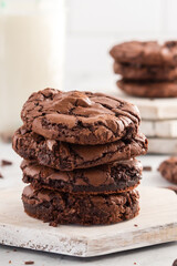Fudgy brownie cookies stacked with a glass of milk in a rustic setting