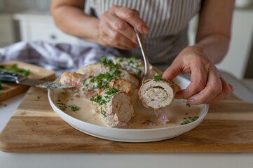 Woman serving a homemade food with fresh braised turkey or chicken roulades filled with cream cheese. 