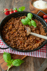 Original ragu alla bolognese served ready to eat in casserole on rustic and wooden table background