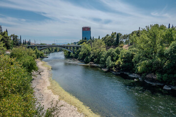 Fototapeta premium Podgorica, Montenegro, August 5, 2024.Ribnica River and Montenegro Flag on Bemax Building