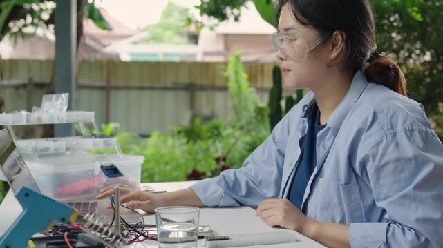Asian woman programming microcontroller to control Analog Dissolved Oxygen Sensor to find the appropriate value of oxygen in water for use in agriculture in aquaculture. IoT Internet of Thing.