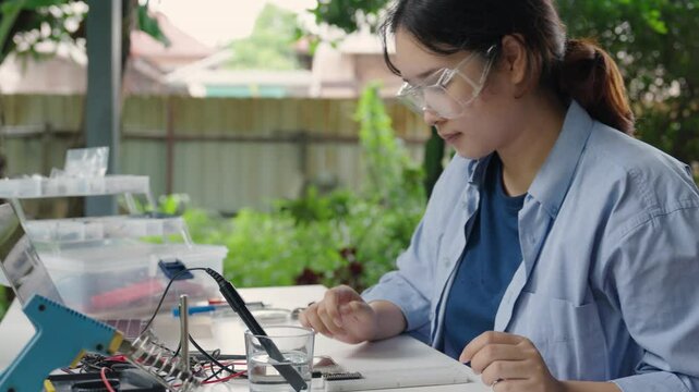 Asian woman tests analog dissolved oxygen sensor functionality with smartphone app, Agriculture and aquaculture, Internet of Things (IoT)