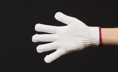 Hand is wear glove knitting on black background.