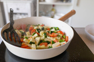 Fresh cubed vegetable frying in a frying pan with steam