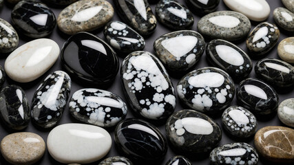 Collection of polished stones with black, white, and gray patterns set against a dark background.