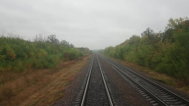 View from the front window of the locomotive of a moving train. Railway. A cloudy autumn day.