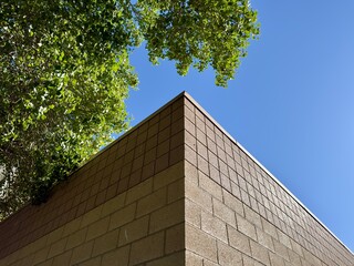 a corner view of a brown-painted block exterior building wall, showcasing its textured surface and sharp angles, offering a glimpse of urban architecture and simple design