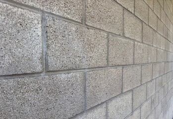 a close-up view of a cinder block exterior building wall, highlighting the rough texture and solid structure, showcasing the strength and durability of the material in a simple, industrial setting
