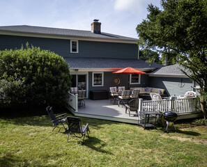 A backyard decks furniture with all the cushions on and a red umbrella