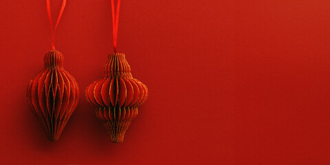 Festive Red Paper Christmas Ornaments, hanging red flashlight or lantern with gold shine on red background, minimal style aesthetic monochrome photo, festive holiday above view banner, copy space