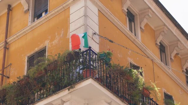 A colorful balcony showcases the essence of Italy with vibrant flags and luscious plants